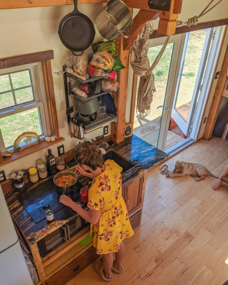 Timber Frame Tiny House on Wheels, Clara making lunch on the induction cooktop in the galley kitchen